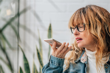 woman talking on mobile phone with hands free or sending voice message