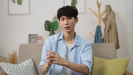 webcam view asian male creative worker working from home is expressing ideas to client with hand gestures in a virtual meeting via video call in the living room