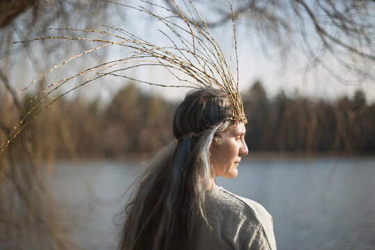 Close up middle age woman with willow branches crown portrait picture. Pagan theme. Closeup side view photography with blurred background. High quality photo for ads, travel blog, magazine, article