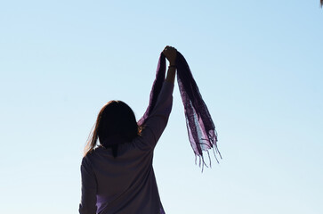 Woman raising a lilac feminist scarf in protest against gender violence