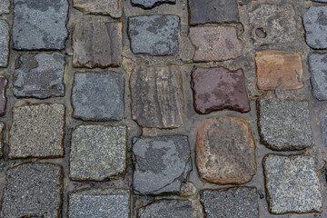 Granite dirty paving stones in the city. Road from paving stones for background and texture. The old road of granite paving stones