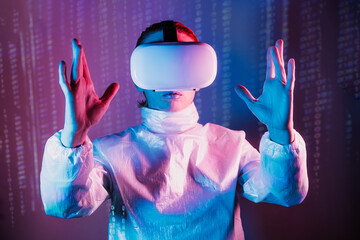 Metaverse concept. Woman in holographic clothes and vr glasses on matrix code background, playing video games with virtual reality headset, trying to touch something with hand in pink blue colors.