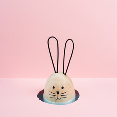 Easter bunny or rabbit peeking out a hole, spring holiday greeting card, pink pastel color,...