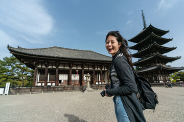 portrait of attractive asian Taiwanese girl turning to smile at camera with gojunoto pagoda of...