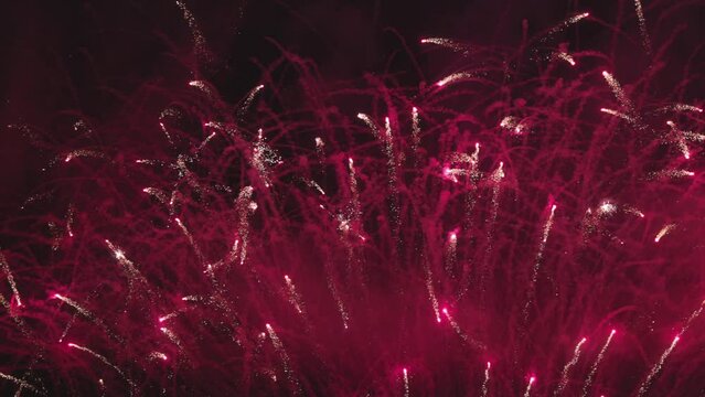 Colorful fireworks festival. Beautiful red fireworks close-up view in slow motion. Wonderful real fireworks in the night sky shot with a telephoto lens. fireworks show. 4K slow motion.