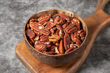 Pecan on dark background. Pecans in a coconut bowl. healthy fat. Heap shelled Pecans nut. Close up. Keto diet. Studio shoot. close up