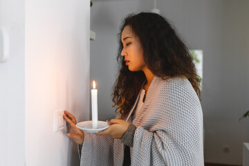 Energy crisis. Hand in complete darkness holding a candle trying to turn on light during a power...