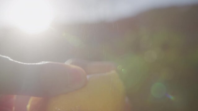 Macro shot of hands opening a lemon and zest oil sprayed in the light