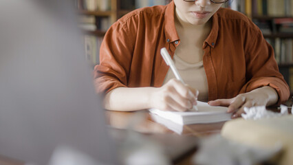 Close-up of young woman brainstorming ideas on paper, looking for inspiration