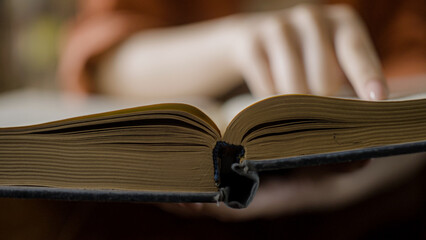 Woman reading large old book, writer doing research in city library, close-up