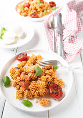 Pasta with tomato mozzarella sauce, parmesan cheese and roasted cherry tomatoes on a plate on white background