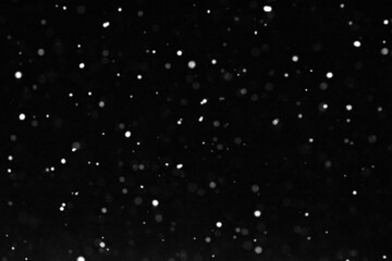 Abstract white lights on a black background. Blurry, out of focus image.