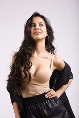 Fototapeta premium Portrait of a young stylish brunette girl with wavy hair on a white studio background.