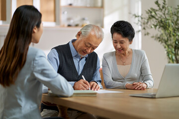 senior asian couple signing a contract at home