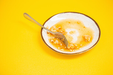 dirty plate with honey and pie crumbs on yellow background