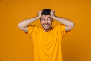 Young white man smiling and grabbing his head in panic