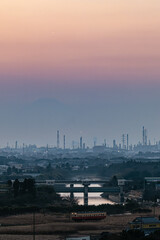 美しいグラデーションの夕焼けとうっすら富士山が見える京葉工業地帯に走る列車