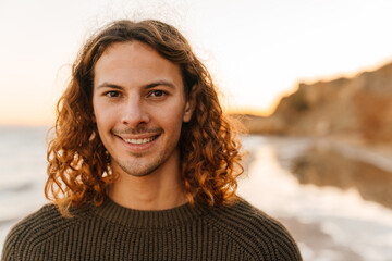 Young smiling man walking at sunny beach