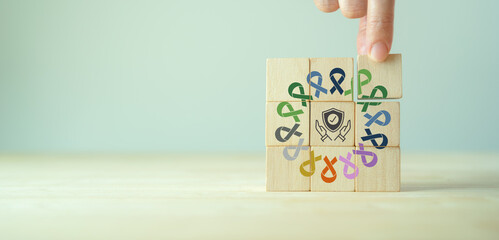 Cancer health insurance concept. Colorful ribbons with insurance icon on wooden cube blocks...