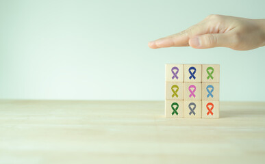 World cancer day (February 4). Colorful ribbons on wooden cube blocks background, cancer awareness, national cancer survivor day, world autism awareness day. Healthcare and medical concept.