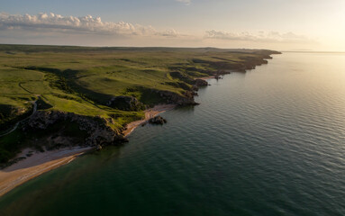 Aerial view of beach. Big hills around. Sunny day at dawn. Greenish sea. Drone Photo.