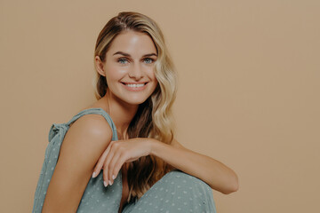 Naklejka premium Fashion studio shot with smiling woman in evening dress sitting on chair