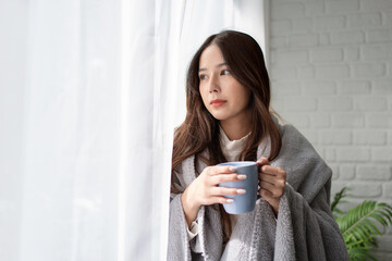 Portrait of Beautiful asian woman in casual clothes standing by large window She looking outside and drinking tea