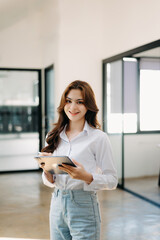 Attractive Asian female office worker business suits smiling at camera in office .