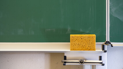 School classroom background - Empty green school blackboard with sponge, close-up detail