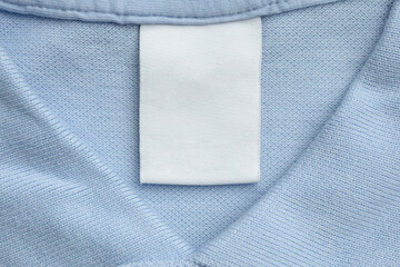 White blank laundry care clothes label on blue shirt fabric background