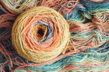 Ball of yarn from pure organic sheep's wool on an unwound skein of woolen threads. Rainbow color. Top view.