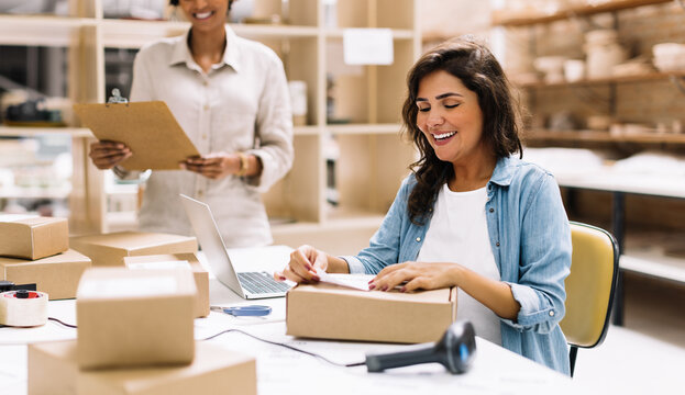 Happy female entrepreneur preparing an online order for shipping