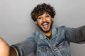 Young Indian man doing selfie shot pov on mobile phone on grey background