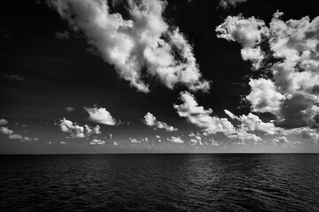 Dramatic sea view, monochrome  seascape, white clouds dark deep ocean bay. Coastline in black and...