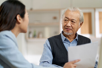 asian old man appears to be unconvinced while listening to a salesperson - obrazy, fototapety, plakaty