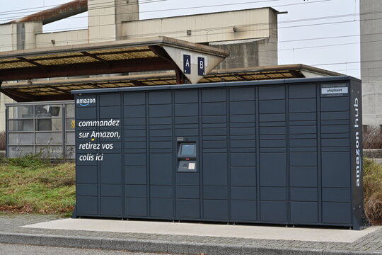 Altkirch, France, 01 01 2023, Amazon Hub lockers placed on a parking lot. Is is self pick-up service with title in French language saying, order on Amazon, pick your parcel here. 