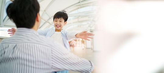 Happy cheerful Asian little boy running to his father at the railway or sky train station after his father returned from the traveling trip. Happy Asian family father and son concept.