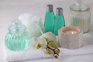 Spa Komposition mit Massageöl, Kerzen und Orchideenblüte.