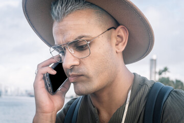 young man with a hat and talking on cellphone with worried expression.