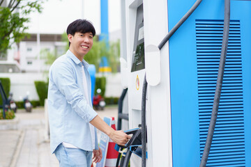 Fototapeta premium Unrecognizable Asian man holding AC type 2 EV charging connector at EV charging station.