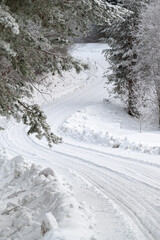 Fototapeta premium Snowy winter road curve with the frosty trees along the side