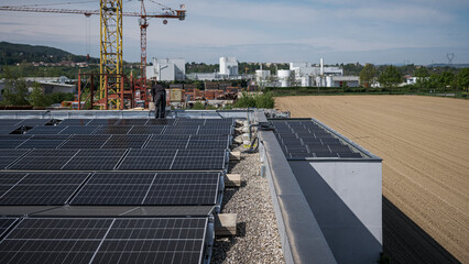 Male team engineers installing stand-alone solar photovoltaic panel system. Electricians mounting blue solar module on roof of company roof. Alternative energy concept