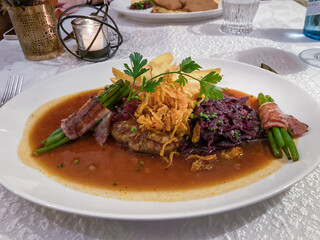 Main course, roast beef with onions and red cabbage, beans and bacon on a finely decorated table, Hesse, Germany