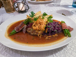 Main course, roast beef with onions and red cabbage, beans and bacon on a finely decorated table, Hesse, Germany