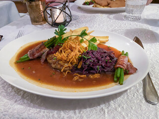 Main course, roast beef with onions and red cabbage, beans and bacon on a finely decorated table, Hesse, Germany