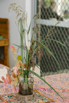Common reed grass and lilly pilly leaves in a small container with water and rocks