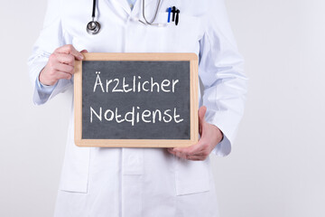 Arzt mit einer Tafel auf der Ärztlicher Notdienst steht