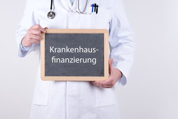 Arzt mit einer Tafel auf der Krankenhausfinanzierung steht