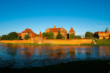 Naklejka na ściany i meble Marienburg Castle the largest medieval brick castle in the world in the city of Malbork at sunset