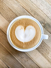 A cup of coffee latte on a wooden table. A mug of flat white coffee, latte, cappuccino on a wooden background. Coffee art. Heart flower shape latte art